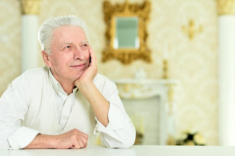 Content Elderly Man Resting Chin on Hand in Assisted Living Facility