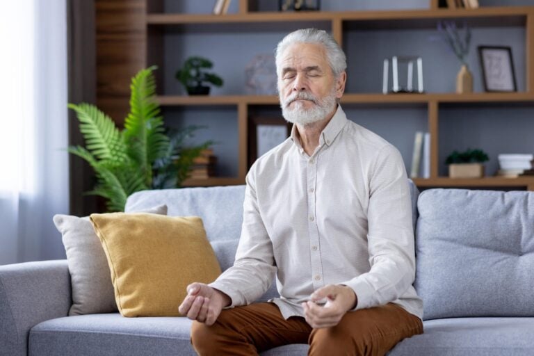 Elderly Man Meditating Peacefully on Sofa in Memory Care Community