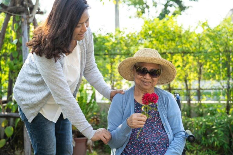 Female Nurse Assisting Elderly Woman Outdoors during Respite Care