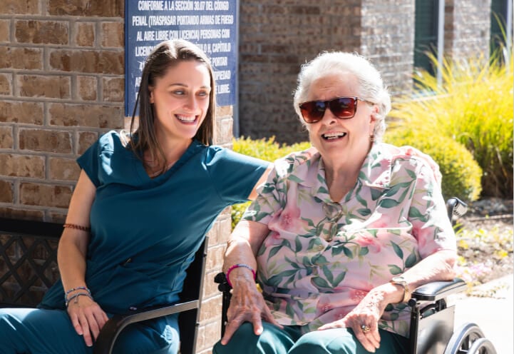 Female Nurse Sitting Outdoors With an Elderly Resident at an Memory Care Facility Female Nurse Sitting Outdoors With an Elderly Resident at an Memory Care Facility